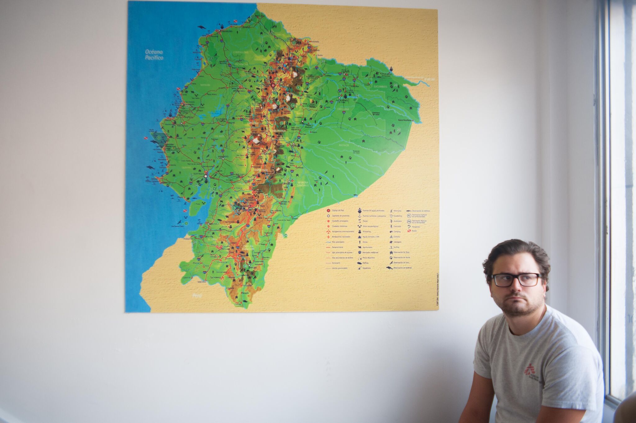 Man sitting next to a big map of Ecuador,
